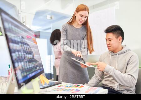 Young woman as web developer together with graphic designer on computer in office Stock Photo