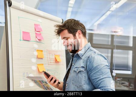 Business man or graphic designer using smartphone in front of a flipchart with organization chart Stock Photo