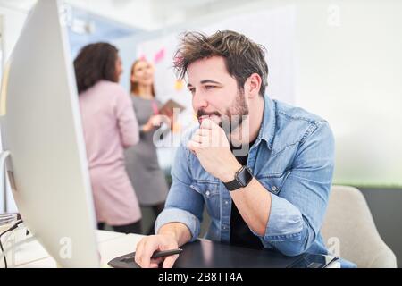 Young business man in the office working on the computer or researching the internet Stock Photo