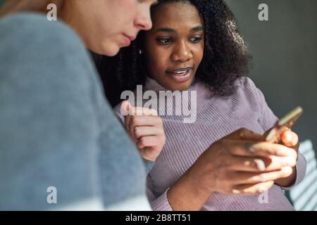 African business woman with colleague reading text message on smartphone Stock Photo