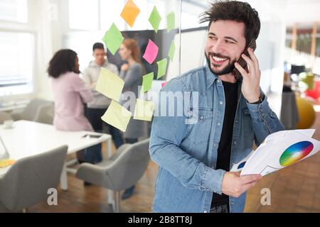 Web designer as a start-up founder calls on the smartphone in the web agency Stock Photo