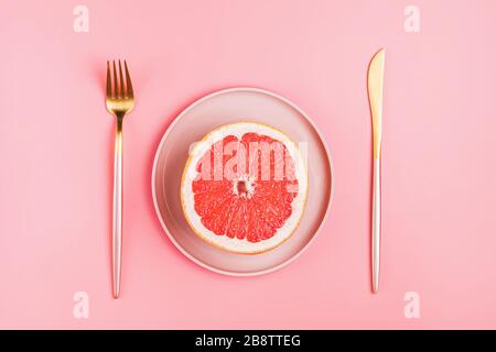 Half a grapefruit on a pink plate on a pastel background Stock Photo