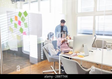 Three young entrepreneurs in a meeting in their internet agency's office Stock Photo