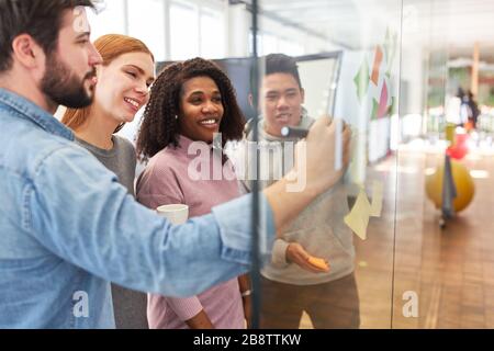 Creative start-up business team brainstorming with sticky notes on glass wall Stock Photo