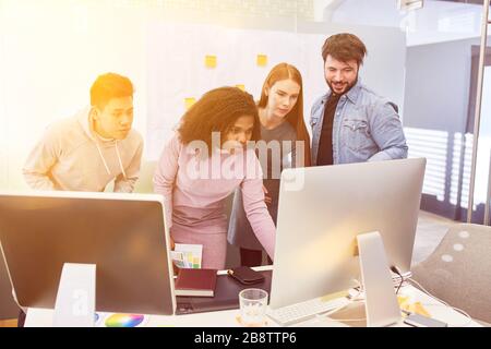 Team of web designers stands together in the office on the computer working together Stock Photo