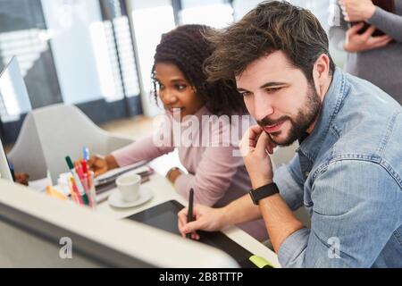 Graphic designer and African colleague on the PC work together on a project Stock Photo