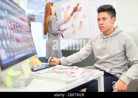 Asian man as a programmer and web developer on the PC of an internet agency Stock Photo