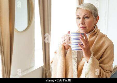 Sad woman holding a mug in her hands Stock Photo
