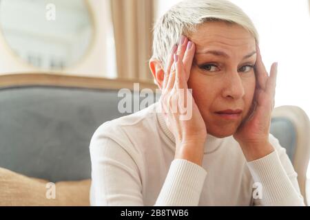 Despondent grey-haired female staring at the camera Stock Photo