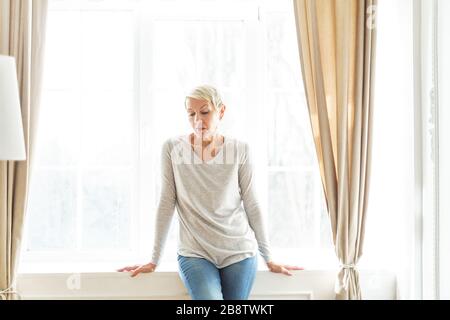 Depressed grey-haired elderly Caucasian lady looking down Stock Photo
