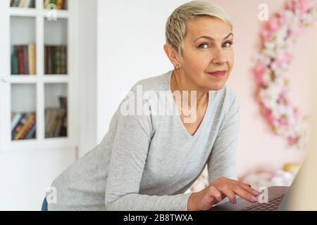 Calm female freelancer leaning over her laptop Stock Photo