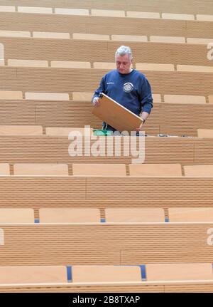 23 March 2020, Brandenburg, Frankfurt (Oder): Peter Frederick, building technician at the European University Viadrina, repairs defective tables in an empty lecture hall. Brandenburg's universities and the Ministry of Science have jointly decided to shut down operations at the universities to an emergency presence mode starting this week until further notice. At the TH Wildau and the FH Potsdam the emergency operation will start on Monday, March 23rd, at the other universities on Tuesday, March 24th. Photo: Patrick Pleul/dpa-Zentralbild/ZB Stock Photo