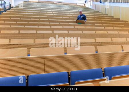 23 March 2020, Brandenburg, Frankfurt (Oder): Peter Frederick, building technician at the European University Viadrina, repairs defective tables in an empty lecture hall. Brandenburg's universities and the Ministry of Science have jointly decided to shut down operations at the universities to an emergency presence mode starting this week until further notice. At the TH Wildau and the FH Potsdam the emergency operation will start on Monday, March 23rd, at the other universities on Tuesday, March 24th. Photo: Patrick Pleul/dpa-Zentralbild/ZB Stock Photo