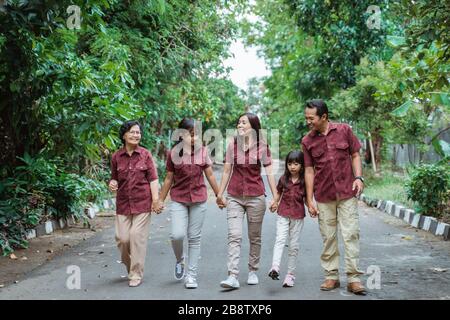 Happy asian family,two daughters, mother, father and grandmother join hands to enjoy walks together Stock Photo