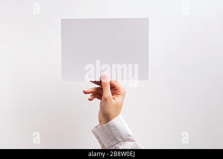 Woman's hand holding white blank paper card Stock Photo
