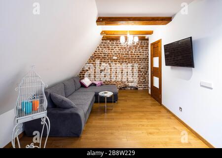 Modern wooden loft interior of apartment. Cozy sofa and TV. Private house. Brick wall. Decor. Stock Photo