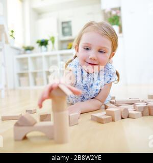 Child builds house with wooden building blocks at home Stock Photo