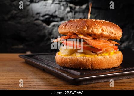 Appetizing fish burger with pieces of red fish meat on a brick wall background. Stock photo burger with fish filling. Stock Photo