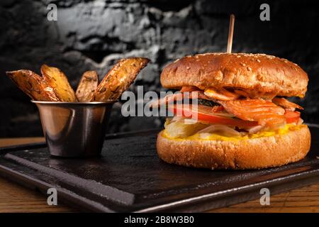 Appetizing fish burger with pieces of red fish meat on a brick wall background. Stock photo burger with fish filling. Stock Photo
