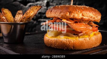 Appetizing fish burger with pieces of red fish meat on a brick wall background. Stock photo burger with fish filling. Stock Photo