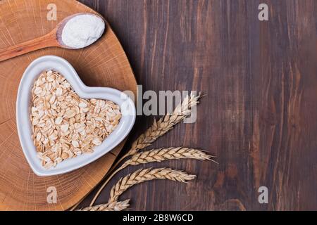 Oats, wheat ears and flour in the spoon on the wooden table, top view. Stock Photo