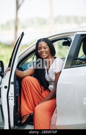 Pretty young smiling Black woman with dreadlocks sitting in her new car Stock Photo