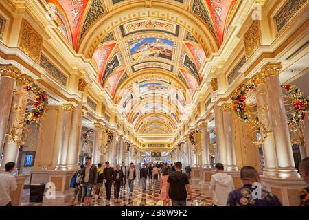 Tourists walking in a brightly illuminated hall of the luxurious Venetian Macao Resort Hotel. Cotai, Macau, China. Stock Photo