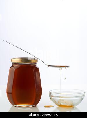 Honey in a glass bottle with spoon on the top isolated white background Stock Photo