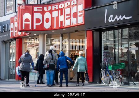 Hanover, Germany. 23rd Mar, 2020. People stand in a queue in front of a pharmacy. Credit: Julian Stratenschulte/dpa/Alamy Live News Stock Photo