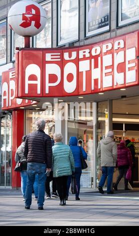 Hanover, Germany. 23rd Mar, 2020. People stand in a queue in front of a pharmacy. Credit: Julian Stratenschulte/dpa/Alamy Live News Stock Photo