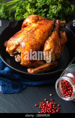 Food concept Roasted, Grilled Whole organic chicken in skillet iron pan on black slate stone board background Stock Photo