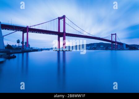 Wakato Bridge is a red suspension bridge that connects Wakamatsu ward and Tobata ward in Kitakyushu City in Fukuoka, Japan. Stock Photo