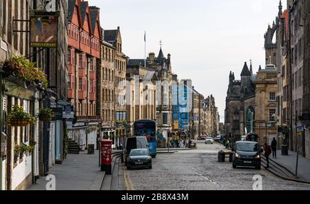 Edinburgh, Scotland, United Kingdom. 23rd March, 2020. Empty streets during the Covid-19 Coronavirus pandemic in the capital city as the message to heed the social distancing measures appears to have had an effect despite the lovely Spring sunshine. The Lawnmarket on the Royal Mile is deserted apart from the camera crews and photographers visible further down the street outside the High Court waiting for the Alex Salmond trial verdict Stock Photo