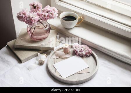 Spring still life scene. Greeting cards mockups, marble tray, cup of coffee, old books. Vintage feminine styled photo, floral composition with pink sa Stock Photo