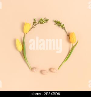 Wreath made of easter eggs and flowers on a beige background. Holiday concept with place for text. Stock Photo