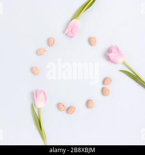 Wreath made of easter eggs and flowers on a blue pastel background. Holiday concept with copy space. Stock Photo