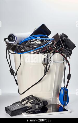 trash can filled with used obsolete electronics, wires, mobile phones, tablet, camera, electrical appliances Stock Photo