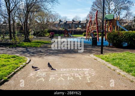 Brunswick Park, Camberwell, London, UK. 23rd Mar, 2020. A message in chalk on the path reminding people to be aware of coronavirus, to adhere to social and physical distancing and keep 2 metres apart. The playground has also been closed as the Government strengthens its advice on social distancing to reduce the spread of the Covid-19 virus. Credit: Tom Leighton/Alamy Live News Stock Photo