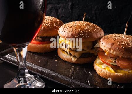 Cold beer in a glass and a snack in the form of juicy large burgers. Fast food. Stock Photo