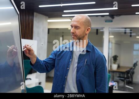Waist up portrait of bald adult man using digital board during training seminar in office, copy space Stock Photo