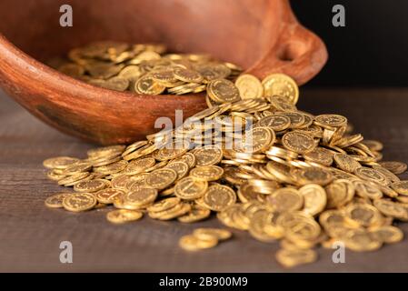 Cascade of small golden coins from a crock pot Stock Photo