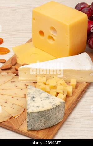 different types of cheese with nuts and dried apricots, grapes and honey on a wooden board. Top view Stock Photo