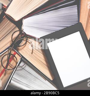 The e-book with a clean white screen rests on the open multi-colored books. ready to read Stock Photo