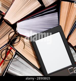 The e-book with a clean white screen rests on the open multi-colored books. ready to read Stock Photo