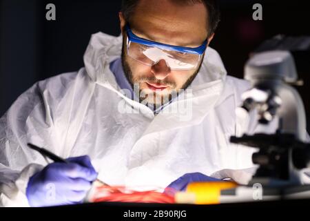 Man laboratory repairs instrument near microscope Stock Photo