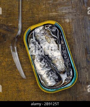 Open tin of sardines with a perspex fork shot from above