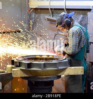 workers in safety clothing sanding a casting in an industrial company Stock Photo