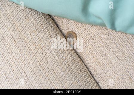 Pound coin falling down the back of a sofa. Stock Photo