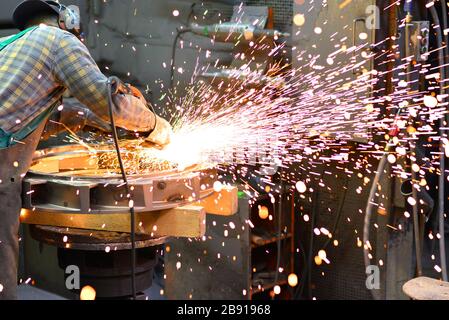 workers in safety clothing sanding a casting in an industrial company Stock Photo