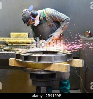 workers in safety clothing sanding a casting in an industrial company Stock Photo